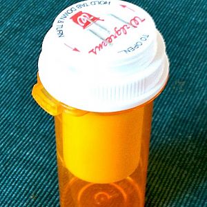 Pill bottle as shave stick holder, with stapled cap